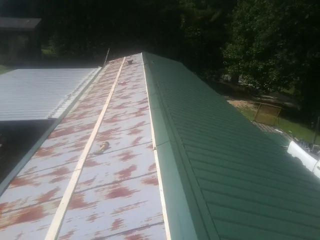 Old rusted panels beside newly installed green metal roofing — Wind Damage Roof Repair by Roofing Brothers in West Columbia