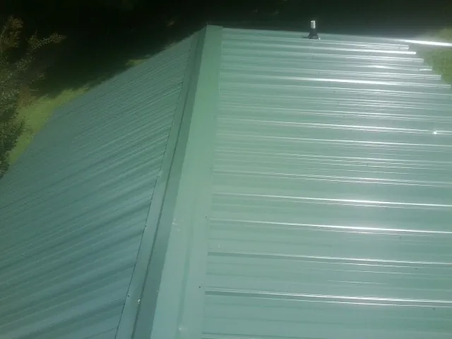 New green metal panels meeting at the ridge of a roof — Flat Roof Repair work by our crew in West Columbia