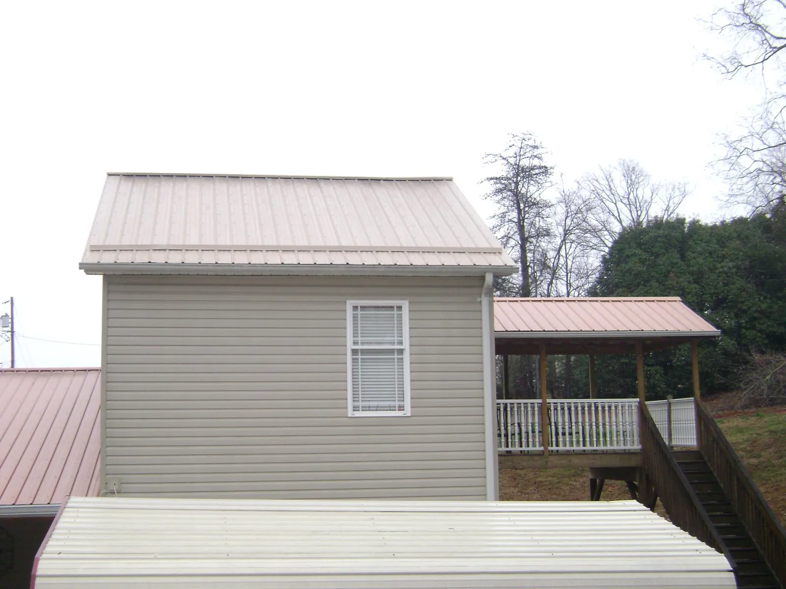 Tan metal roofs on a two story addition and attached porch, from a Roof Replacement job in West Columbia