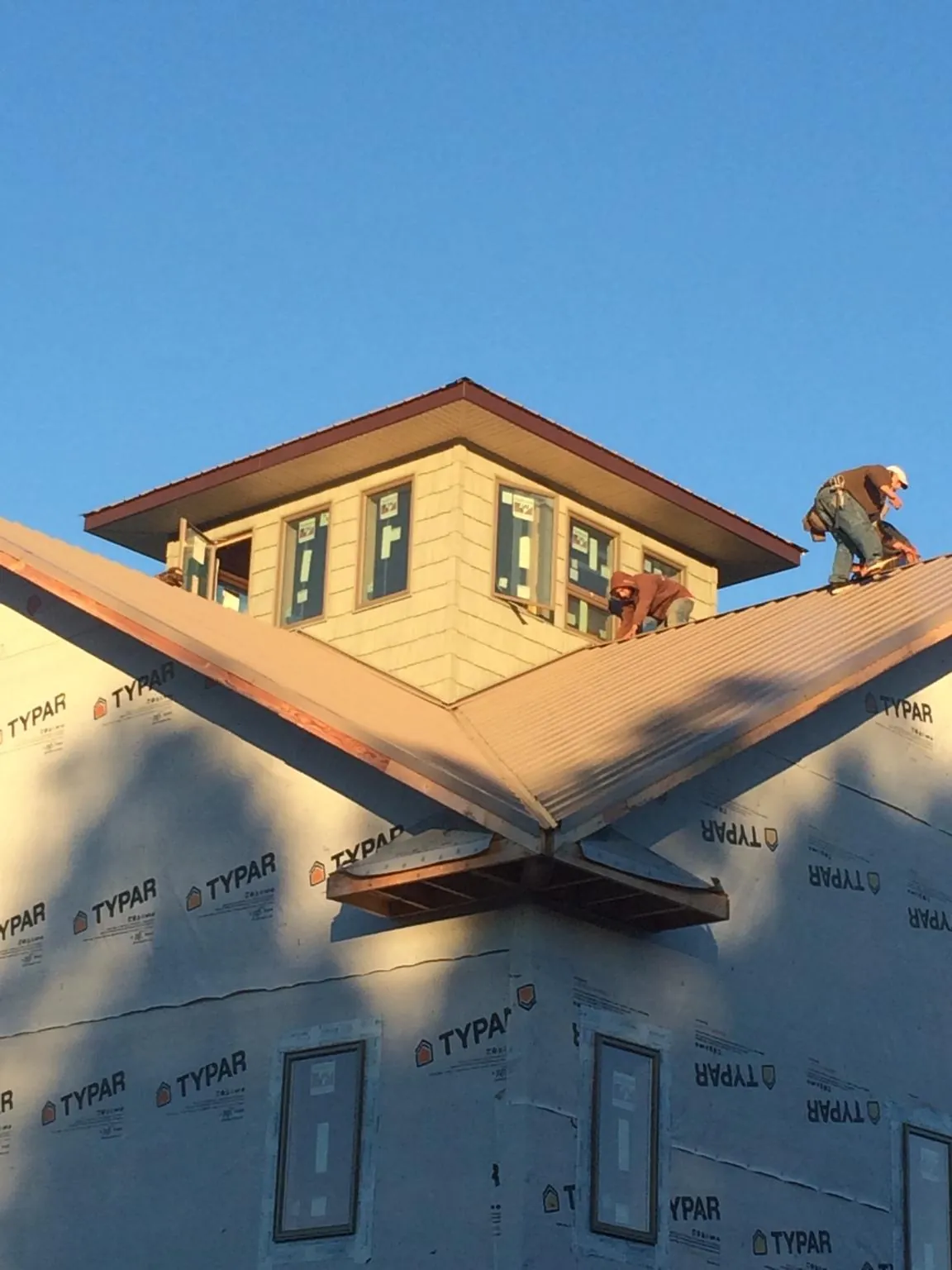 Roofers working around a rooftop cupola on a new metal roof at sunset — Roof Waterproofing in West Columbia by Roofing Brothers